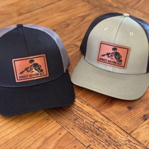 Two caps with outdoor logos on a wooden surface.