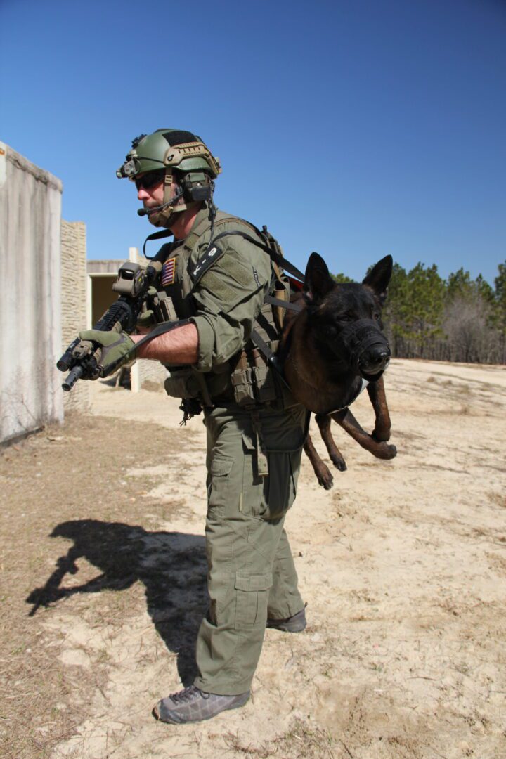 Armed forces member transporting canine.